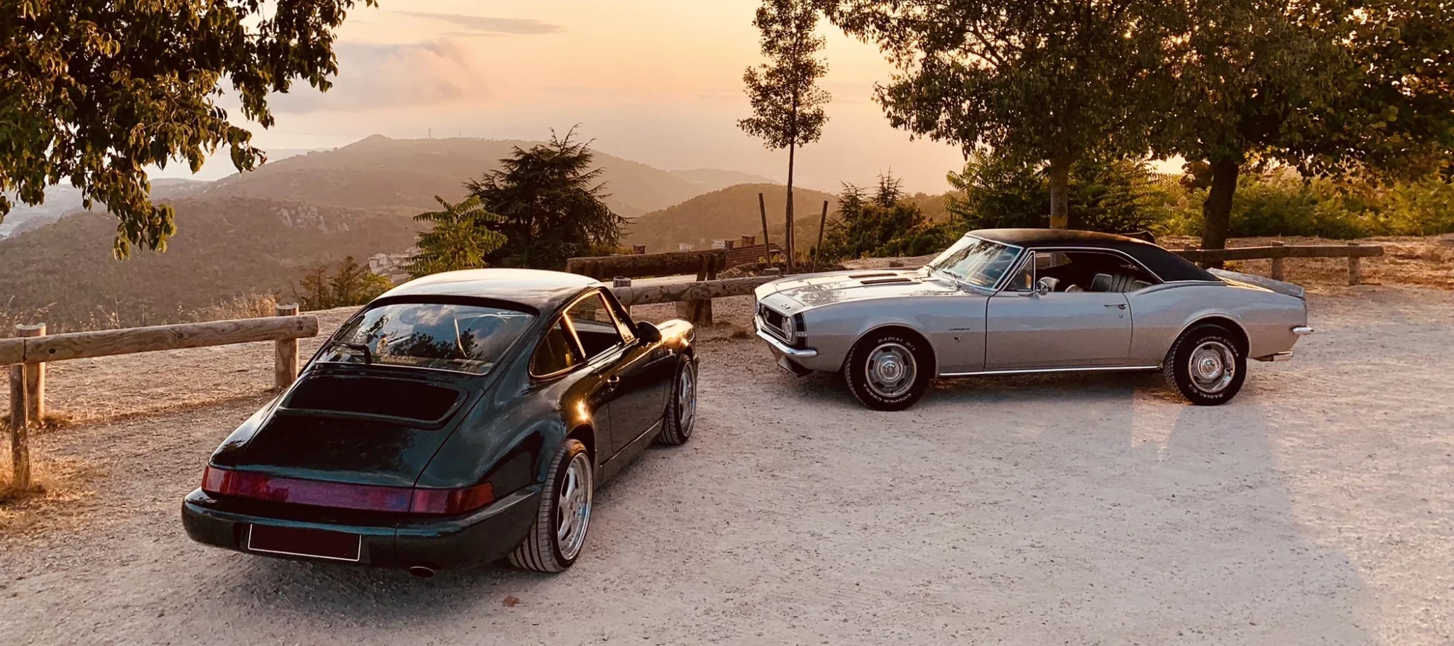 Rear view of a white classic Porsche 911 driving on a winding coastal road.