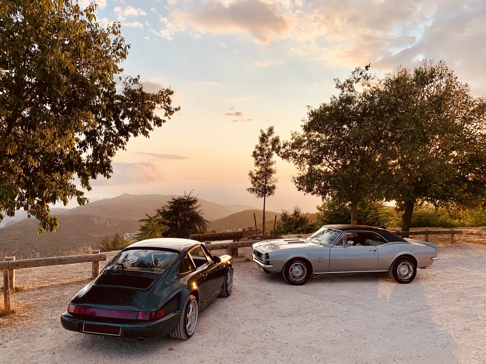 Rear view of a white classic Porsche 911 driving on a winding coastal road.