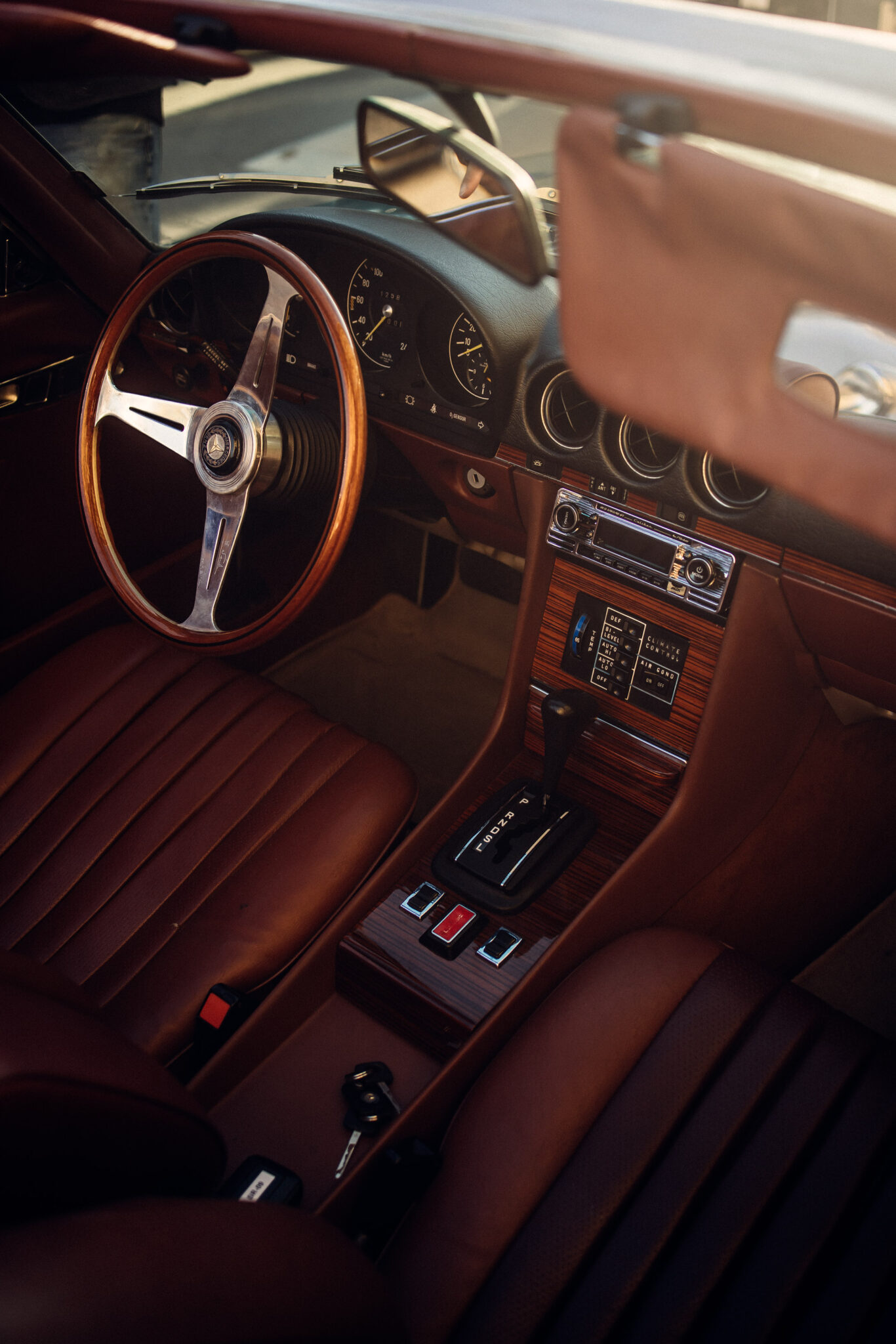 Refined interior of a vintage car with brown leather upholstery and wooden steering wheel, embodying the timeless style featured in 50' Inside.