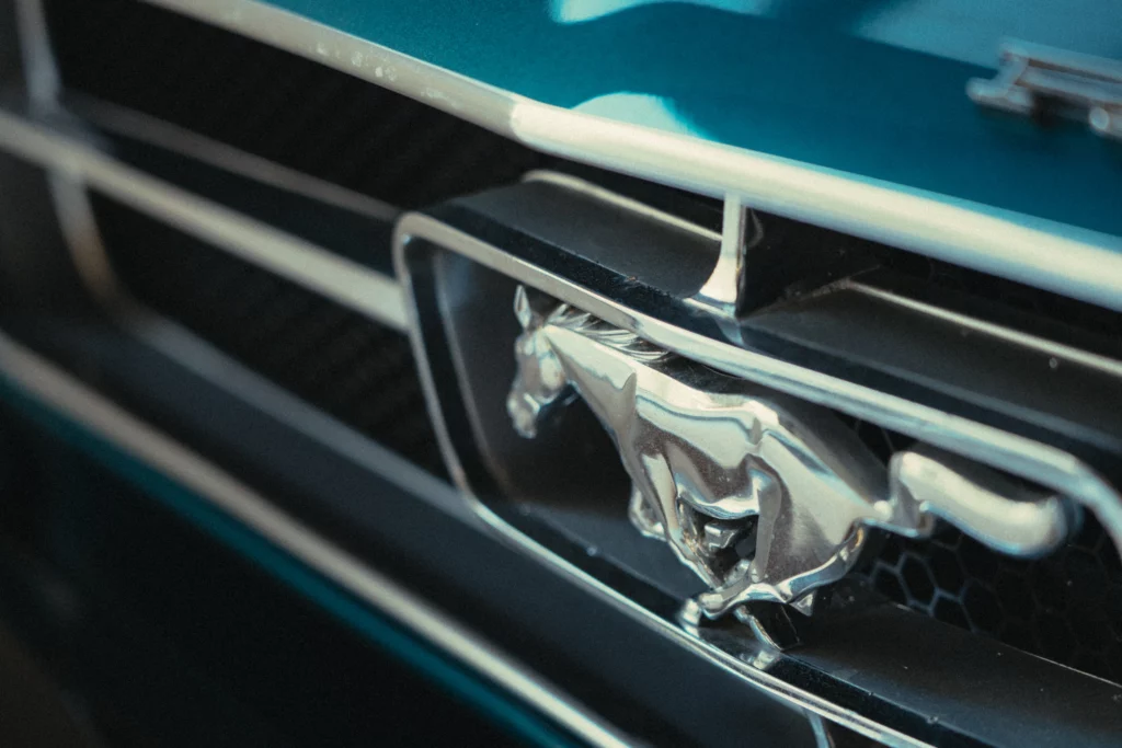 Close-up of Ford Mustang running horse emblem on classic muscle car.